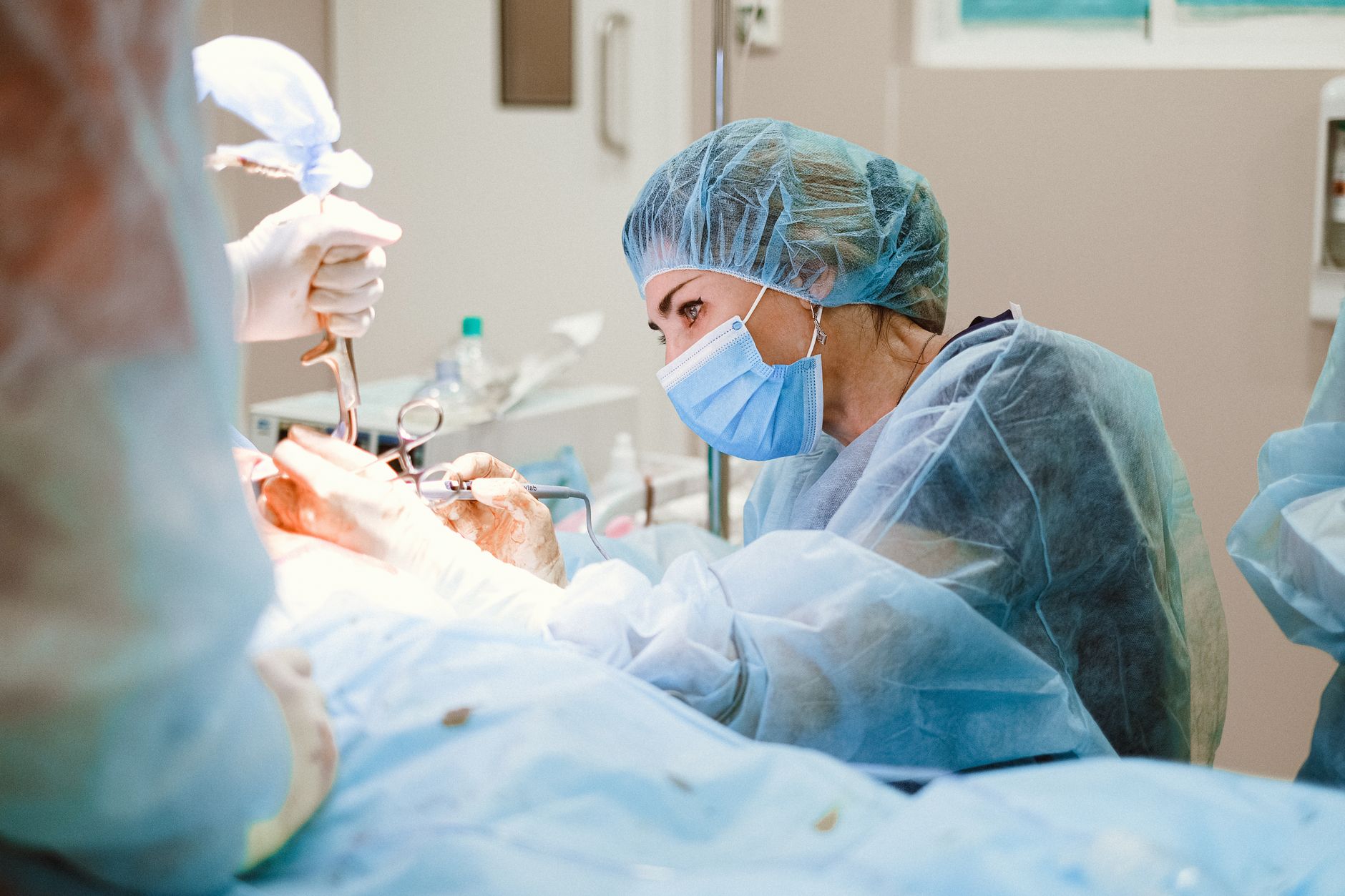 Chirurgienne concentrée sur une procédure complexe dans une salle d'opération stérile, incarnant le professionnalisme dans le domaine de la santé.